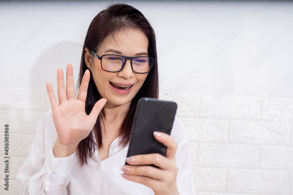 Asian working at home using smartphone, video call meeting with friend.