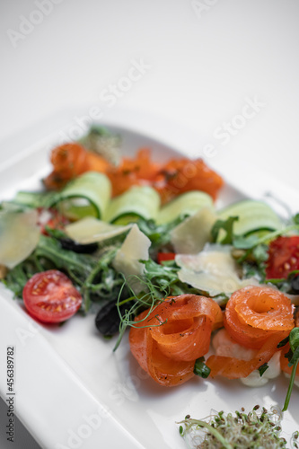 closeup of salad with lightly salted salmon and vegetables on white background