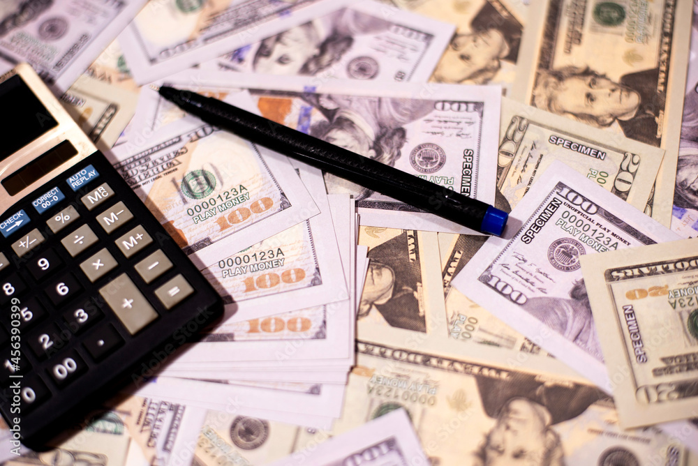 Counting US paper currency in a calculator against us dollar background. Counting US paper currency in a calculator against us dollar background.