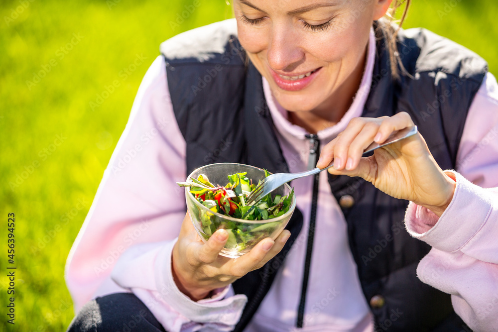 Beautiful caucasian woman eating salad over green natural background
