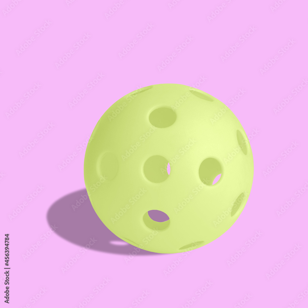 Single yellow pickball isolated on pink background.