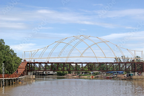Modern bridge with arched beams design over a river against a blue sky background