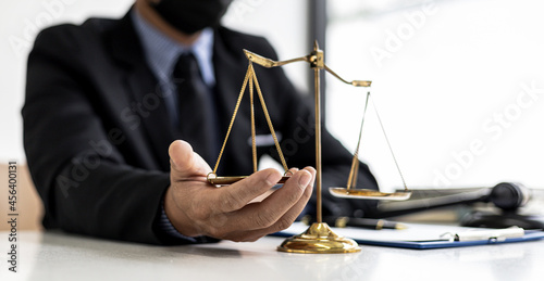 The male lawyer puts a second hand on the scales of justice on his desk, stating that the matter must be justified and not contrary to law and humanity. The concept of legal jurisprudence. photo