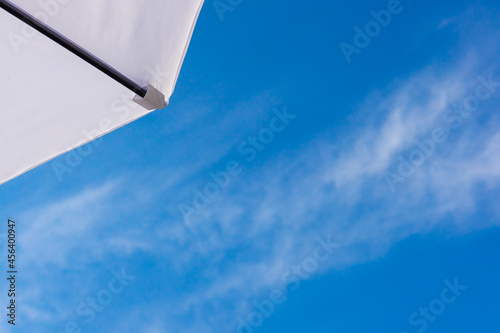 Part of a white beach umbrella on a blue sky background .