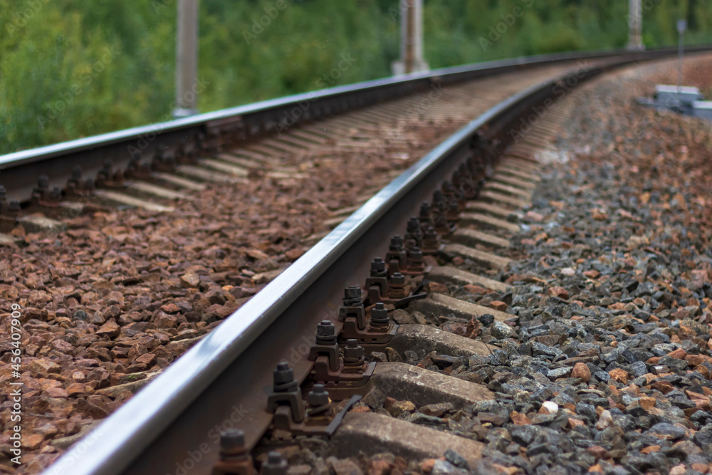Fototapeta premium Railway rails and sleepers close-up. A railway that goes around a bend in the distance.