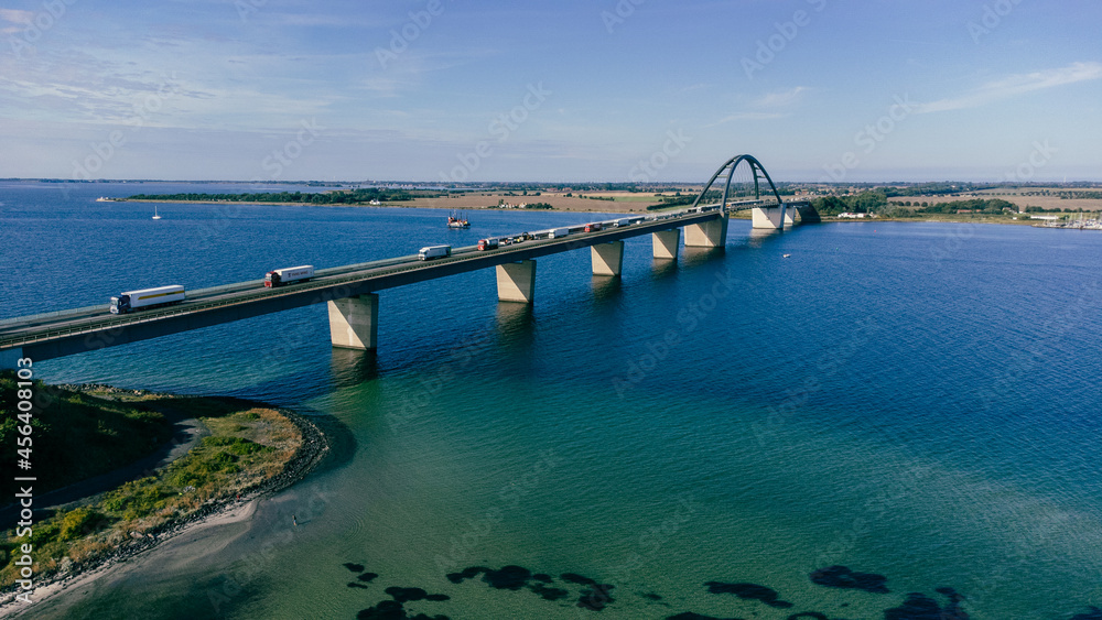 Luftaufnahme einer großen Brücke mit Verkehr über einer Meerenge mit blauem Wasser und vielen Schiffen
