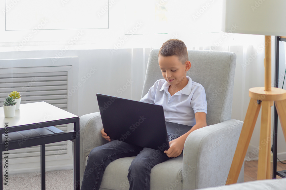 little schoolboy boy does homework on laptop at home. distance learning concept little schoolboy boy does homework on laptop at home. distance learning concept