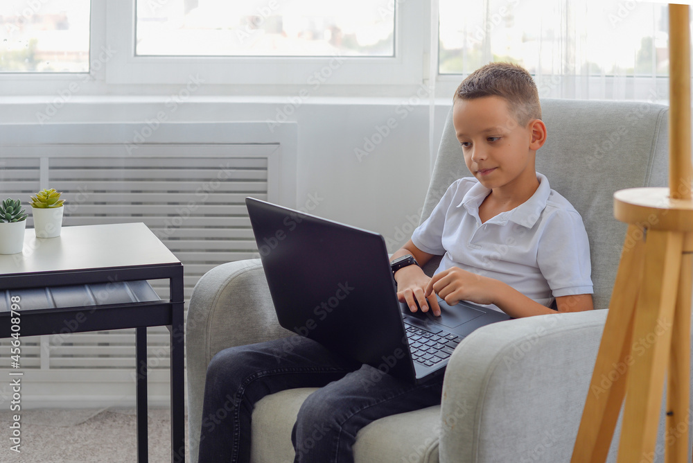 little schoolboy boy does homework on laptop at home. distance learning concept little schoolboy boy does homework on laptop at home. distance learning concept