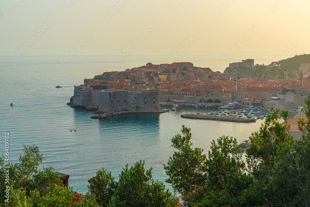 Aerial view of old town of Dubrovnik with Old Port with yachts and boats in blue waters of Adriatic sea at sunset. Dalmatia, Croatia