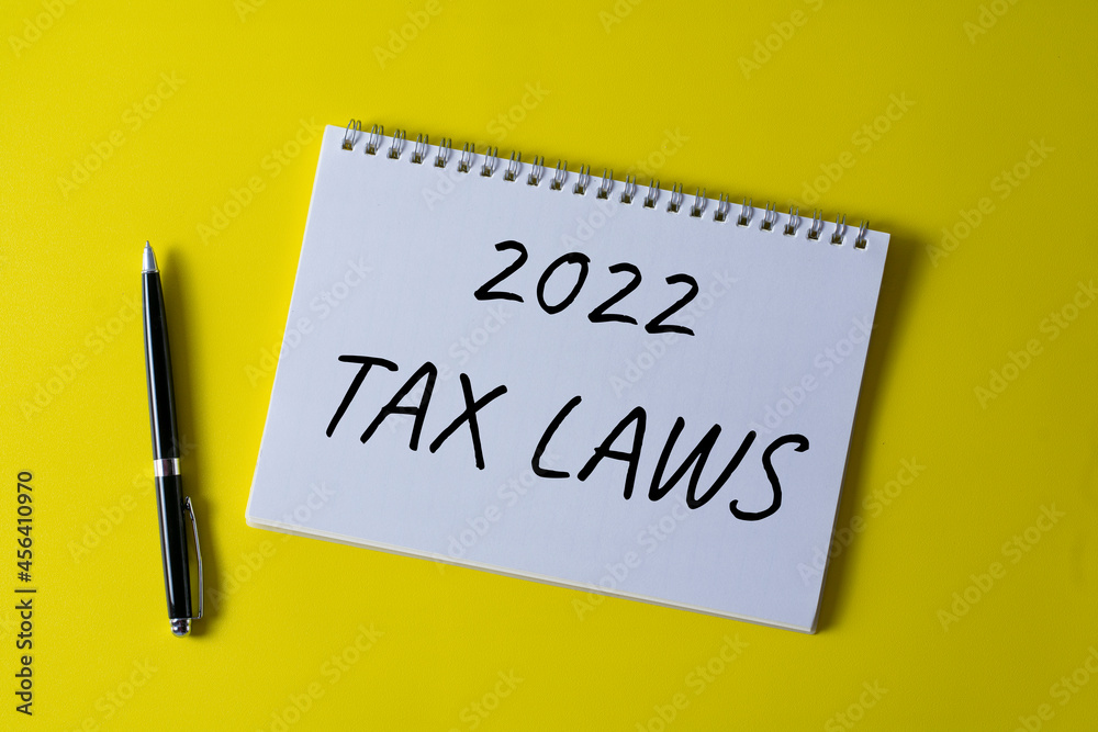 2022 tax laws written in a notebook on yellow background with pen. 2022 tax laws written in a notebook on yellow background with pen.