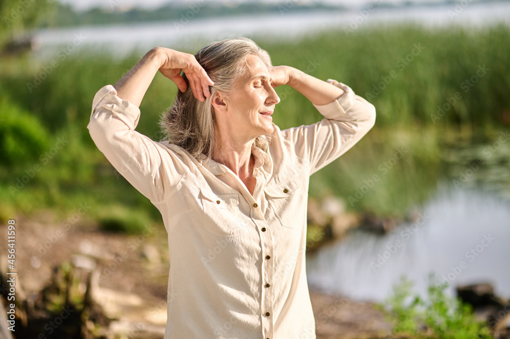 Woman with closed eyes near pond in nature Woman with closed eyes near pond in nature
