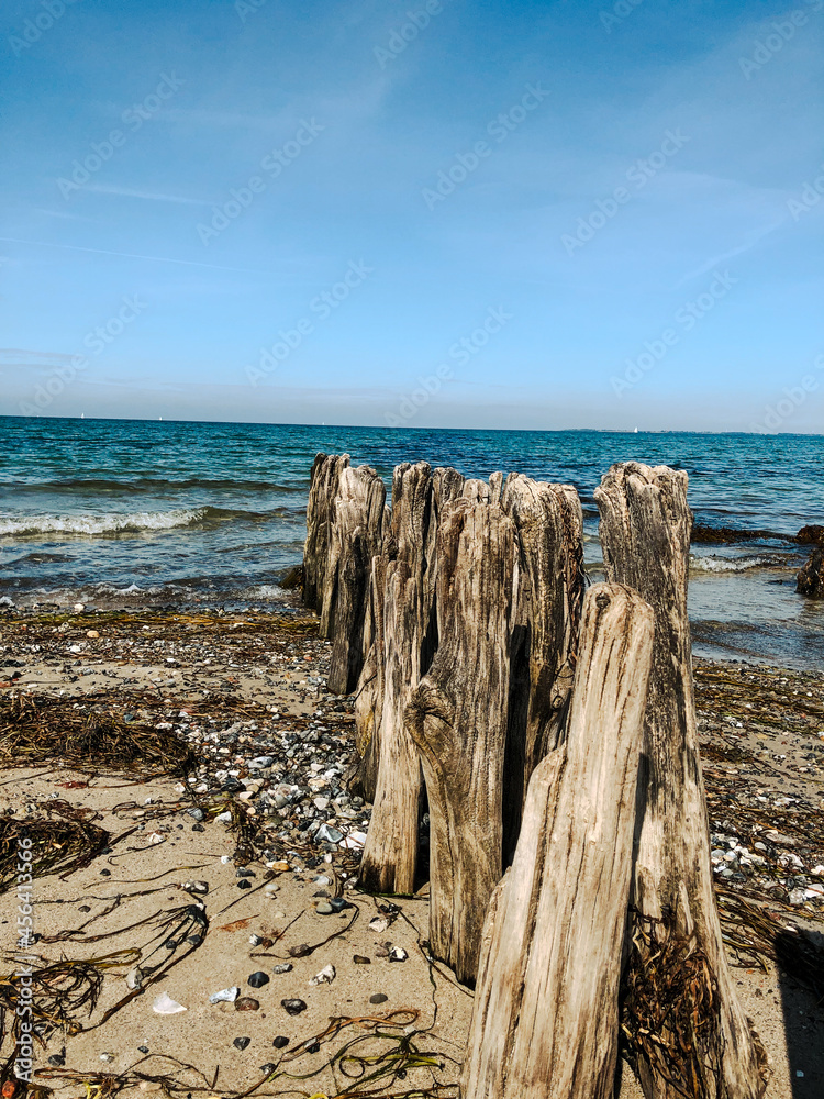 Alte Holzpfähle am Strand direkt ins blaue Meer übergehend Alte Holzpfähle am Strand direkt ins blaue Meer übergehend