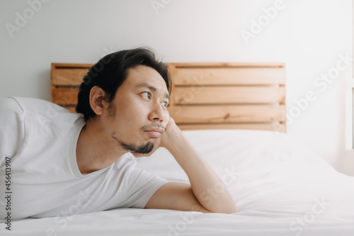 Exhausted Asian man lay on the bed as he feels burnout.