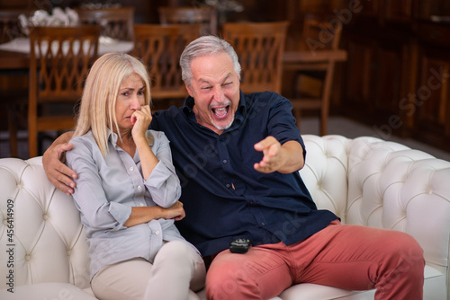 Man having a good laughter, his wife cries while watching the same tv program