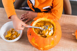 Top view of a boy dressed as a halloween pumpkin emptying a pumpkin to decorate it for halloween