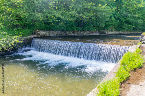 Waterfall on Zylica river among grass and trees at summer time.