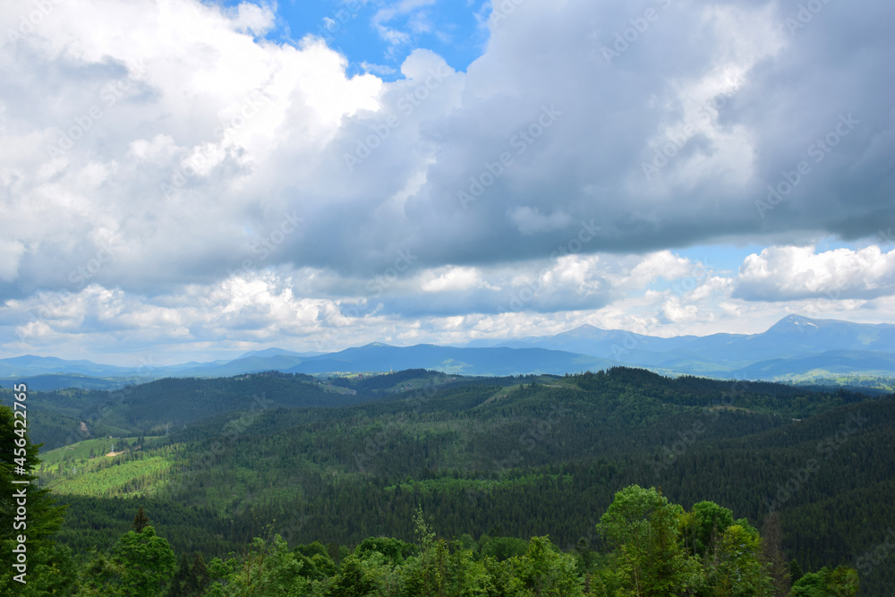 View of the valley from the top of the mountain on a background of several mountains and the sky with clouds