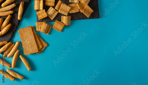 Different types of crusty breads on blue background. Flat lay. Copy space. Snack.