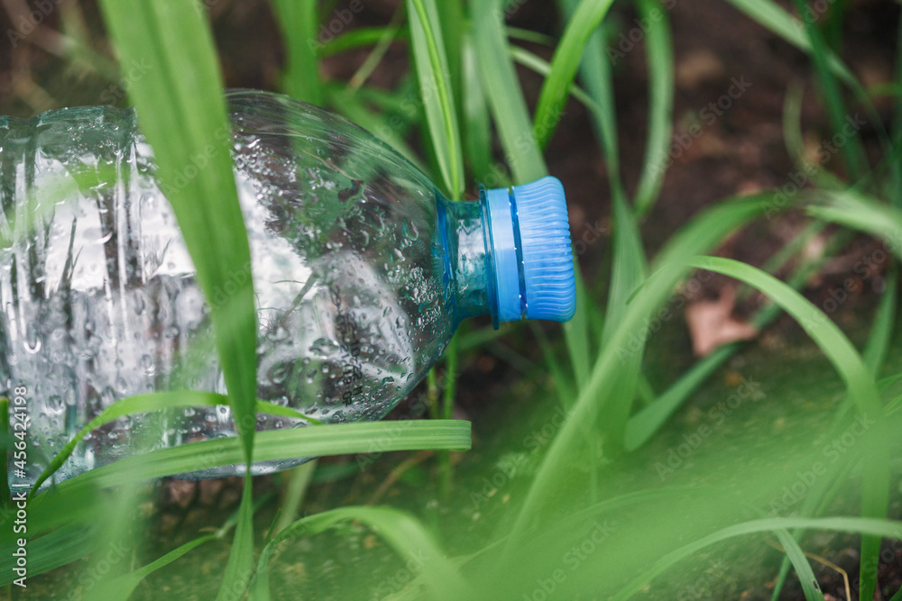 Used plastic water bottle on the grass, waste pollution and recycling concept Used plastic water bottle on the grass, waste pollution and recycling concept