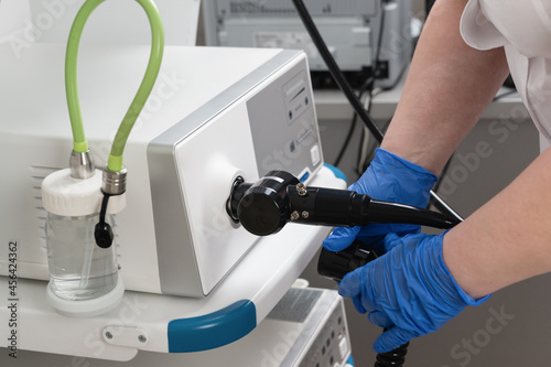 Preparation of equipment for the medical examination of video gastroscopy. The hands of medical worker in blue gloves connect an endoscope and other equipment photo