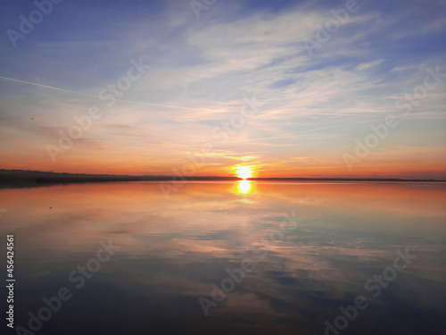 Shatsky Lakes. Ecotourism. Shatsk National Natural Park. Landscape of the setting sun on the lake. Blue skies and gentle water with sun tints. The mirror water of the lake reflects the sky.