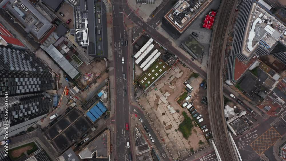 Aerial birds eye overhead top down panning view of traffic on road in business district in city. London, UK