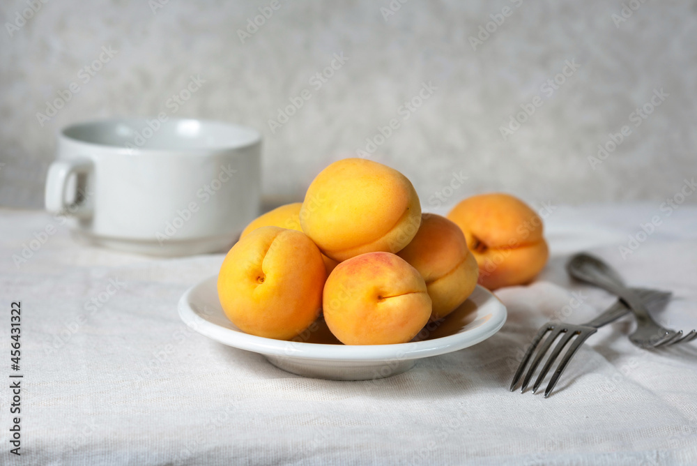 Ripe apricots on a white plate. Delicious vitamin fruit dessert on the table. Selective focus. Ripe apricots on a white plate. Delicious vitamin fruit dessert on the table. Selective focus.
