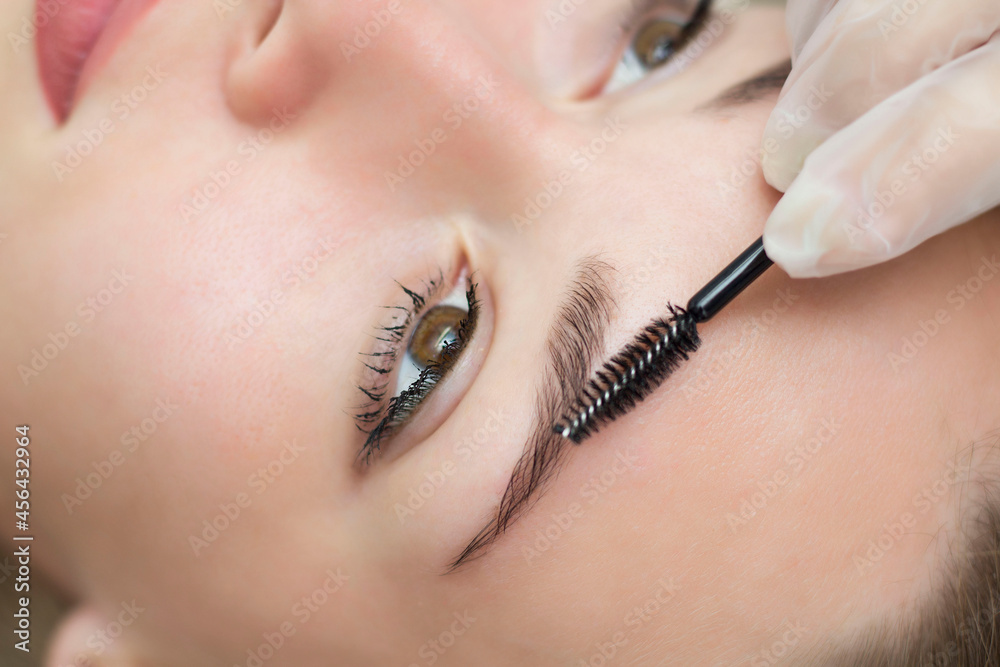 A young woman undergoes the procedure of eyebrow correction, henna staining, lamination. Close-up.