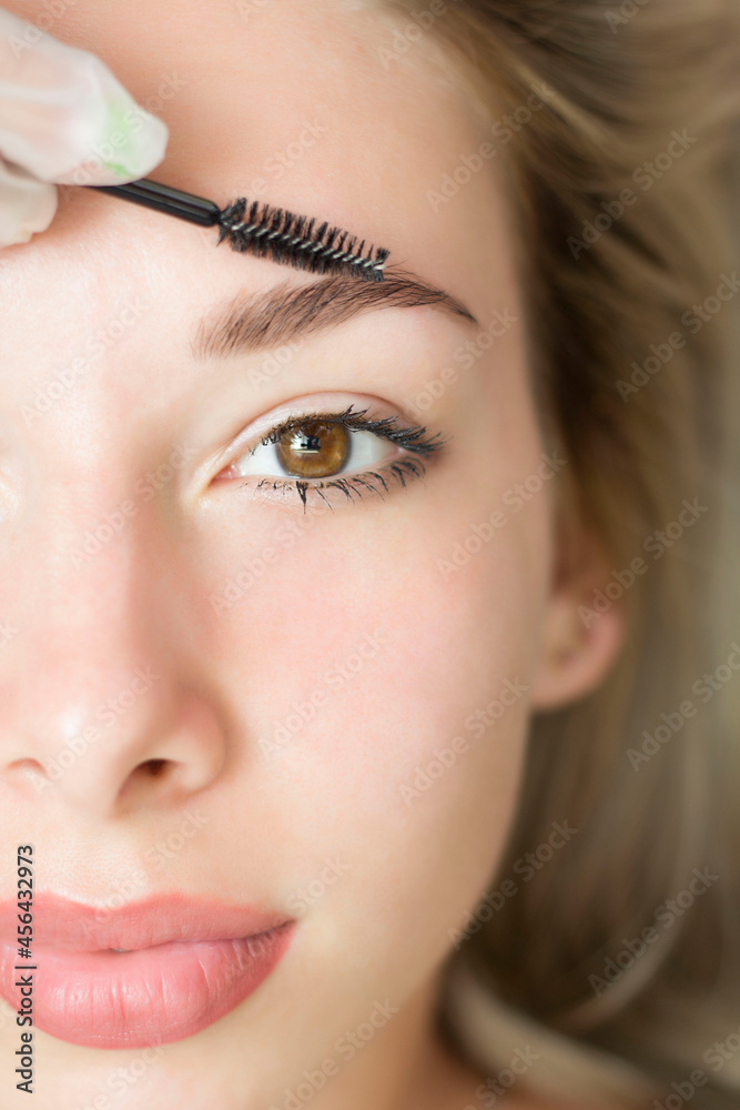 A young woman undergoes the procedure of eyebrow correction, henna staining, lamination. Close-up. Half of the face