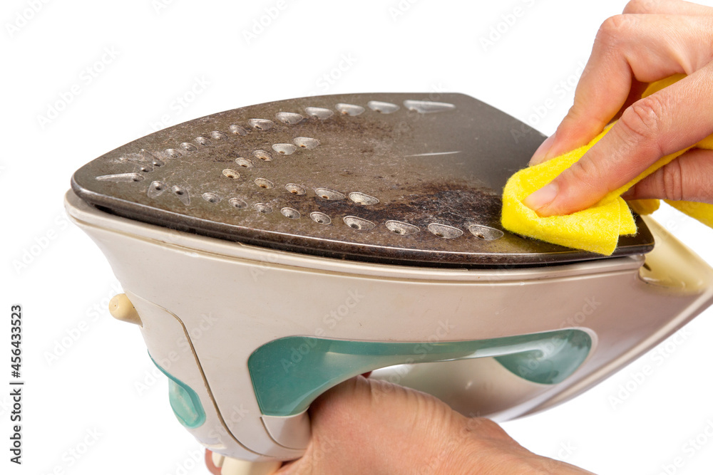 Woman is cleaning the surface of an old dirty iron. The iron has deteriorated. An unsuitable iron will stain clothes.