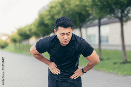Photography Male asian athlete having abdominal pain after fitness in park