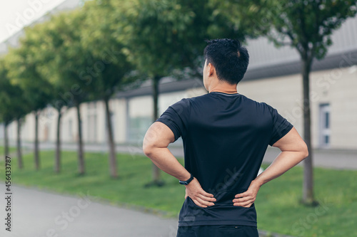 Asian man holding back pain after running and fitness