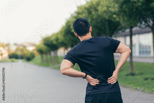 Asian man holding back pain after running and fitness photo