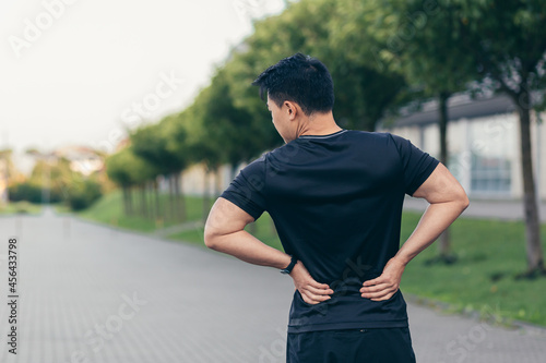 Asian man holding back pain after running and fitness