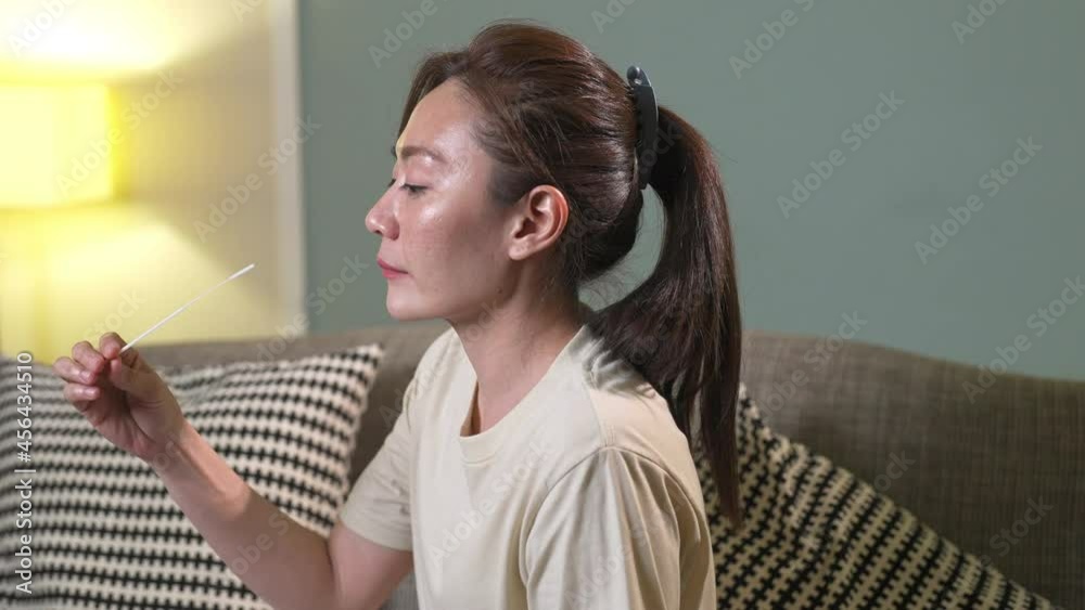 4K Asian woman using rapid antigen test kit for self test COVID-19 epidemic at home. Adult female unpacking a swab for inserts into her nose. COVID-19 coronavirus pandemic protection concept. 4K Asian woman using rapid antigen test kit for self test COVID-19 epidemic at home. Adult female unpacking a swab for inserts into her nose. COVID-19 coronavirus pandemic protection concept.