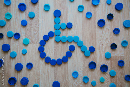 Wheelchair sign from plastic caps. Background of blue plastic bottle caps. Recycling concept. 