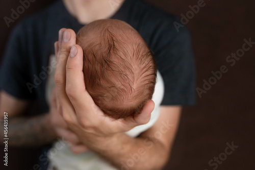 the head of a newborn in the palm of the father. small head of newborn