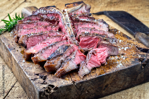 Traditional dry aged barbecue wagyu porterhouse beef steak sliced with herbs and spice served as close-up on a old rustic wooden board