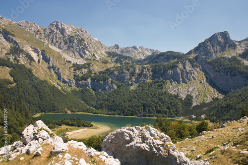 Trnovacko Lake in Montenegro on a sunny day with green hills surrounding it under a clear sk photo