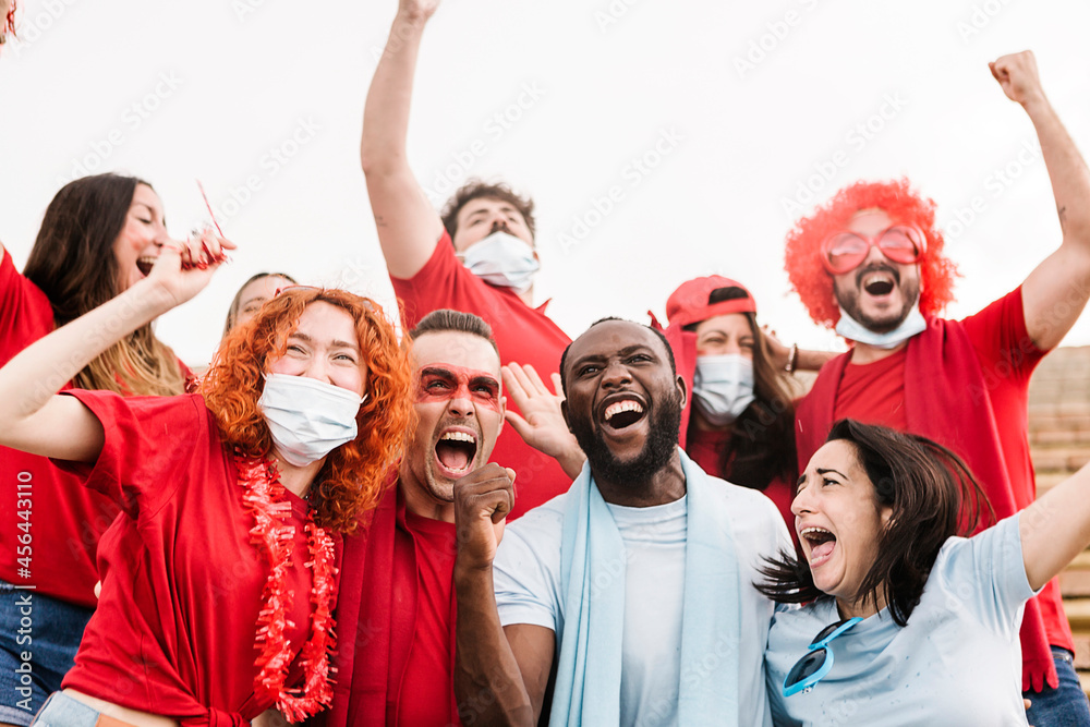 Group of happy multiracial football fans screaming while supporting their team at stadium and celebrating victory - Focus on black man Group of happy multiracial football fans screaming while supporting their team at stadium and celebrating victory - Focus on black man
