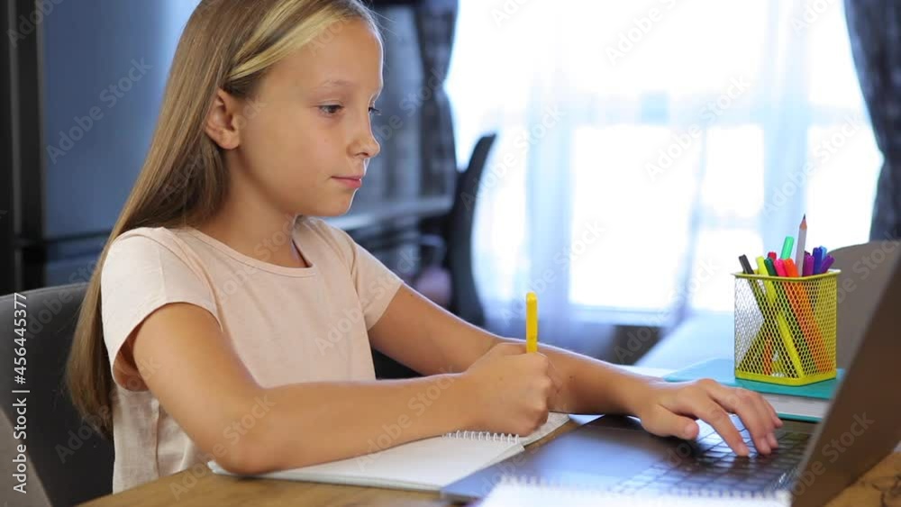 Schoolgirl studies online using a modern laptop. Homework Schoolgirl studies online using a modern laptop. Homework