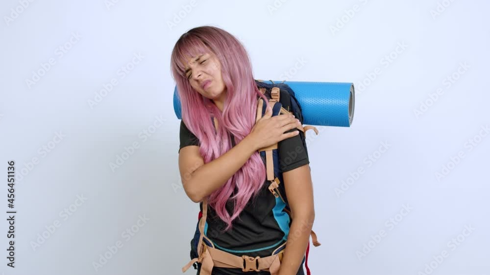 Young woman with pink hair with mountaineering backpack with shoulder pain over isolated background Young woman with pink hair with mountaineering backpack with shoulder pain over isolated background