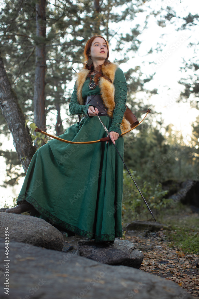 Beautiful red-haired girl-archer of Middle Ages in outdoor. Fantastic concept Beautiful red-haired girl-archer of Middle Ages in outdoor. Fantastic concept