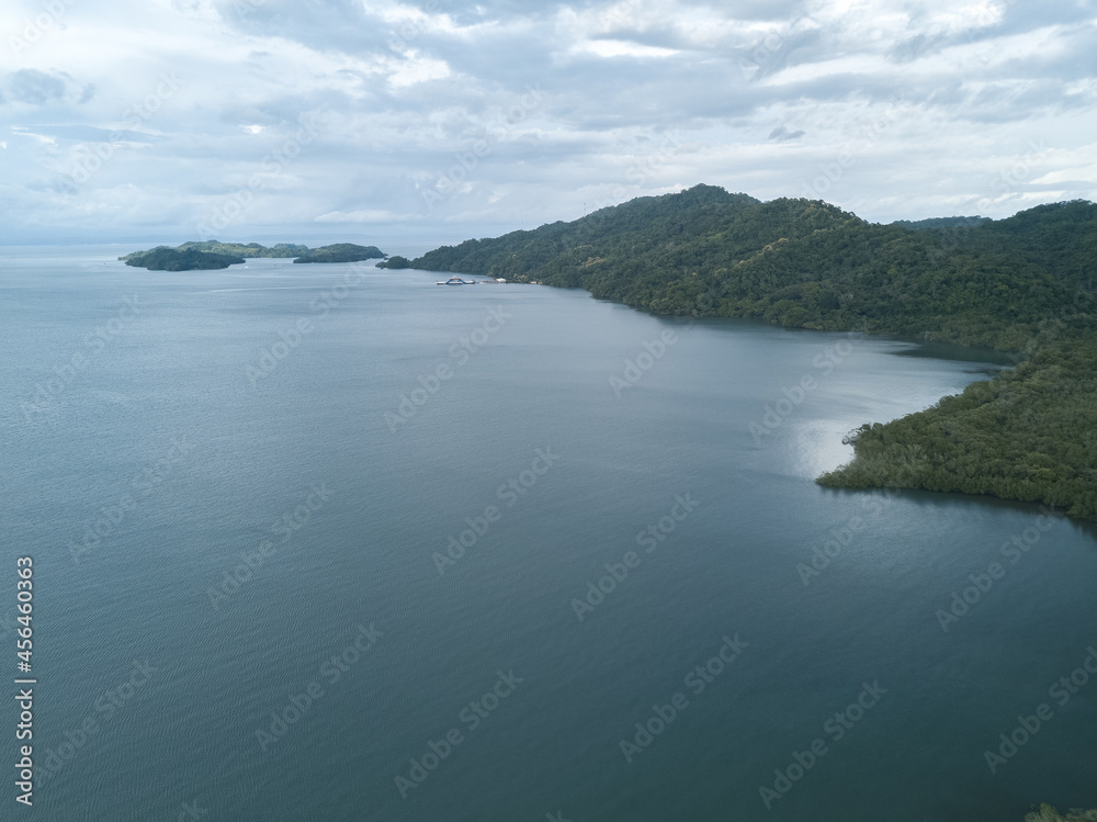 The Paquera-Puntarena ferry terminal seen in the distance surrounded by lush jungles and mountains in a drone aerial image of Paquera Costa Rica