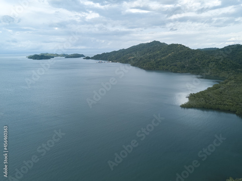 The Paquera-Puntarena ferry terminal seen in the distance surrounded by lush jungles and mountains in a drone aerial image of Paquera Costa Rica