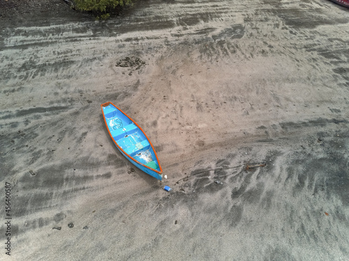 Blue fishing skiff lays on a sandy beach at low tide near Paquera Costa Rica on the Gulf of Nicoya in this aerial drone image