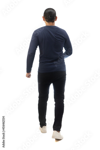 Rear view of a man wearing casual dark blue shirt black denim and white shoes, walking forward, moving with confidence. Full body portrait isolated