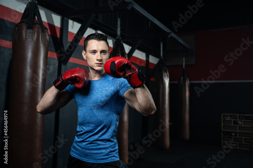 ็Handsome Caucasian men boxer with strong muscle training boxing punch in side of the gym with sandbag. Cardio sport workout activity for good health and build up body and physical strength.