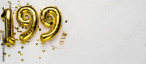 golden foil balloon number one hundred ninety nine. Birthday or anniversary card with the inscription 199. gray concrete background.