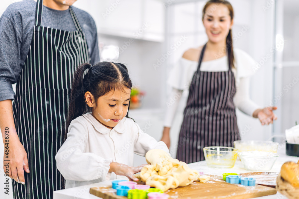 Portrait of enjoy happy love asian family father and mother with little asian girl daughter child having fun cooking food together with baking cookie and cake ingredient on table in kitchen